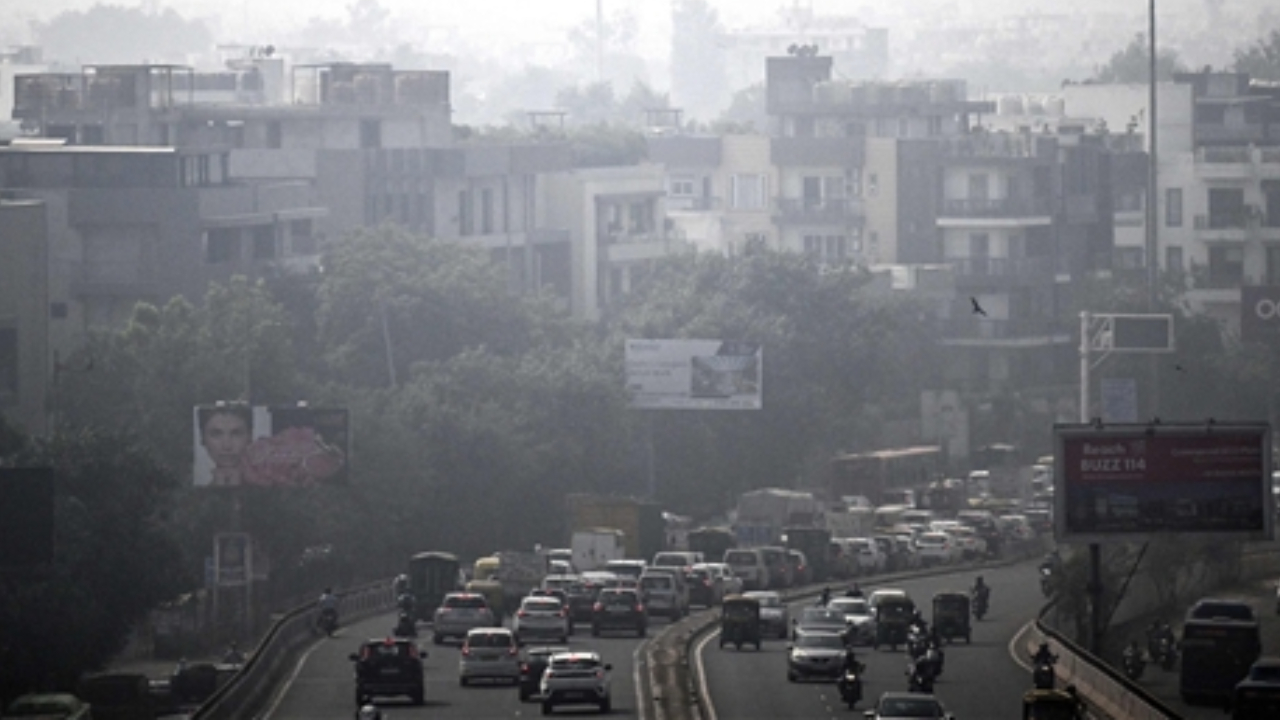 Motorists ride past along a road passing through a residential neighbourhood engulfed in a thick blanket of smog in New Delhi