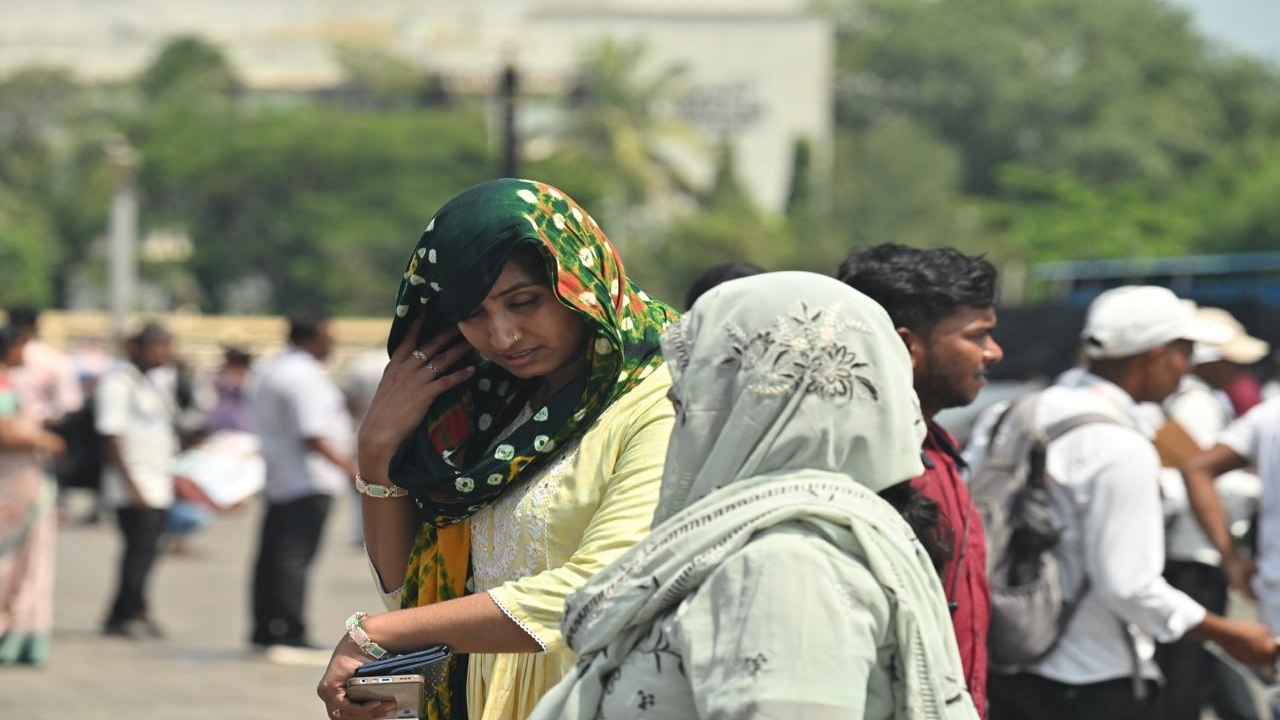 Visitors take steps to protect themselves from the heat at the iconic Gateway of India