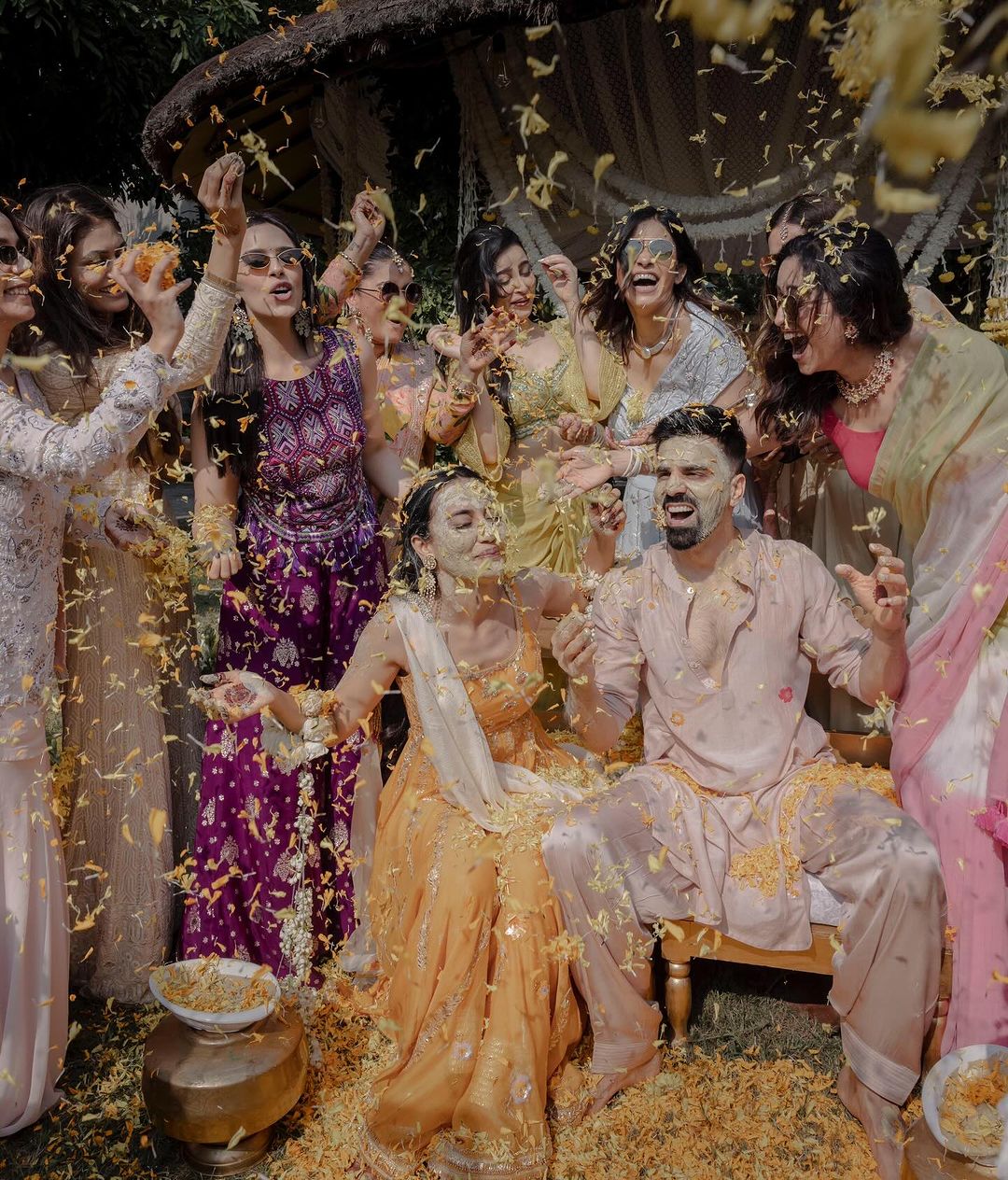 Surbhi Jyoti is dressed in a yellow suit while her friends shower her with flower petals. Sumit Suri is wearing a light pink kurta-payjama